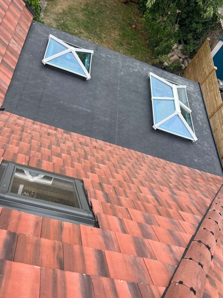 This is a photo taken from the roof ridge looking down a tiled pitched roof on to a flat roof. Works carried out by Radford Roofing Repairs